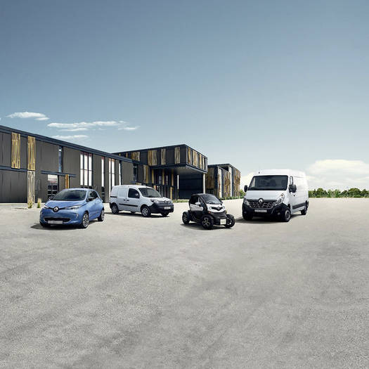 Vier verschiedene Renault Elektroautos stehen auf einem Parkplatz von einem Gebäude