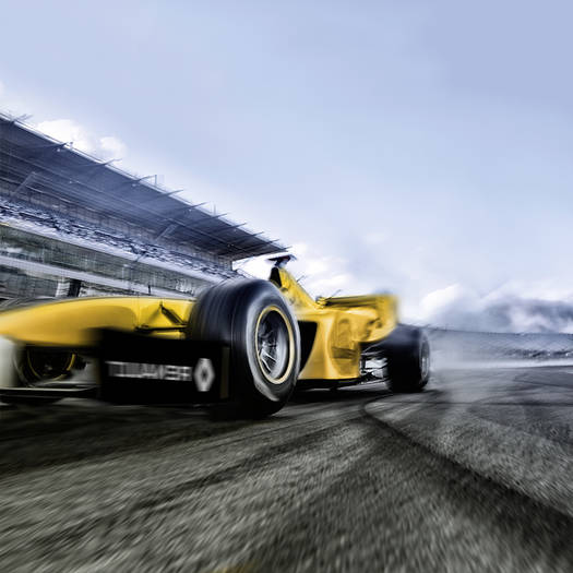 Gelber Formel 1 Wagen fährt auf einer Rennstrecke vor einer Bühne