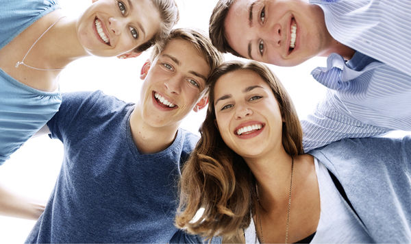 Zwei Frauen und zwei Männer stehen lächelnd Arm in Arm in einem Kreis